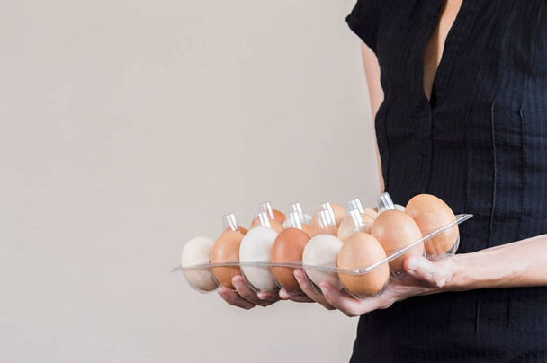 Kaukázusi nő fekete ing gazdaság egy műanyag tojás dobozban, a tyúk-tojás. - Fotó, kép