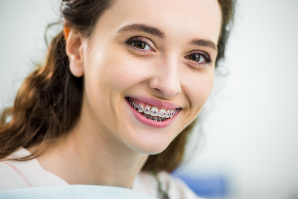 primer plano de la mujer feliz con frenos en los dientes sonriendo en la clínica dental
 - Foto, Imagen