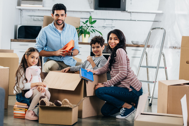 cheerful hispanic family unpacking boxes in new home  - Photo, Image