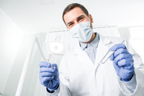 dentist in latex gloves and mask holding dental instruments in hands - Fotoğraf, Görsel