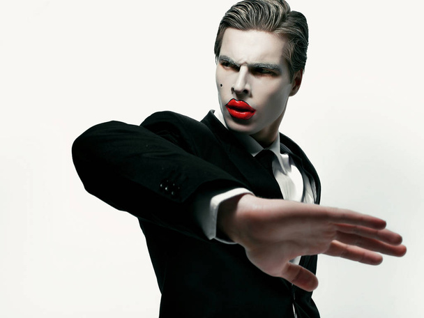 мужская модель с художественным макияжем, позирующая рукой перед камерой
 - Фото, изображение