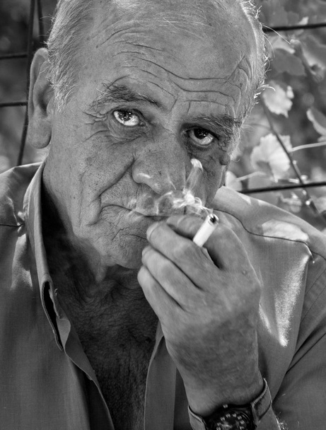 Zbliżenie portret poważne stary grecki piłkarz mężczyzna, który pali papierosa z uśmiechem, czarno-białe - Zdjęcie, obraz