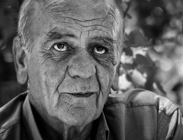 Retrato de primer plano de un viejo y serio griego retirado que fuma un cigarrillo con una sonrisa, en blanco y negro
 - Foto, imagen