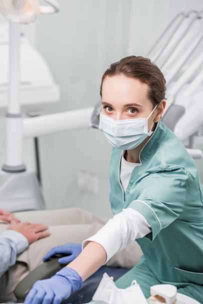 dentista femminile in maschera e guanti di lattice vicino paziente
 - Foto, immagini