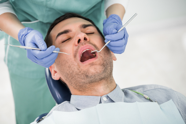 vista recortada del dentista femenino que trabaja con el paciente con la boca abierta
 - Foto, Imagen