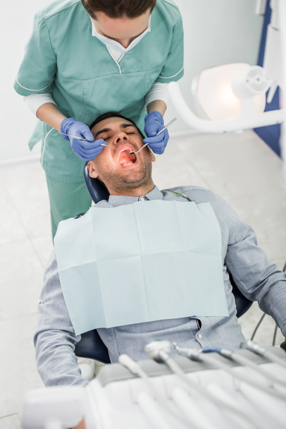 開いた口で患者とともにマスクの女性歯科医 - 写真・画像