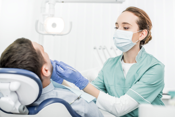 dentista femenina sosteniendo instrumentos dentales cerca del paciente en la clínica dental
 - Foto, Imagen