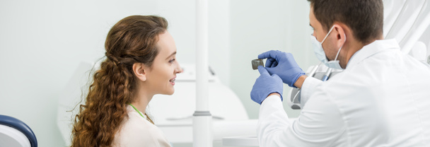 dentista em luvas de látex apontando com o dedo na radiografia dos dentes perto do paciente
 - Foto, Imagem