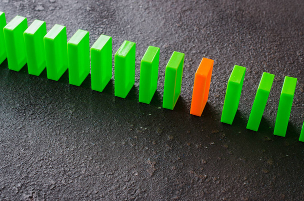 Domino effect - row of green dominoes on dark background. The concept of a weak link. - Фото, зображення