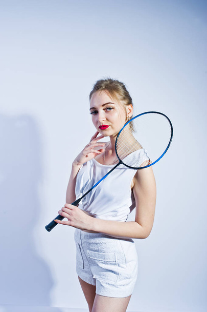 Amazing fit sexy body brunette caucasian girl posing at studio against white background on shorts and top with badminton racket. - 写真・画像