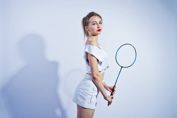 Amazing fit sexy body brunette caucasian girl posing at studio against white background on shorts and top with badminton racket. - Fotó, kép