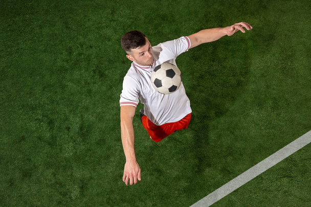 Football player tackling ball over green grass background - Zdjęcie, obraz