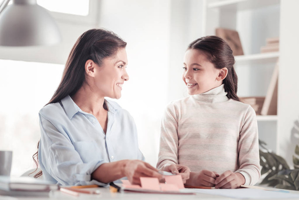 Well-behaved glad daughter helping mother with work - Photo, image