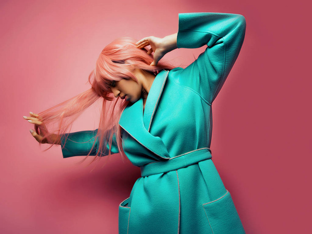 model with pink hair wearing blue suit posing on pink background - 写真・画像