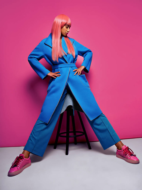 model with pink hair wearing blue suit posing on pink background - Photo, Image