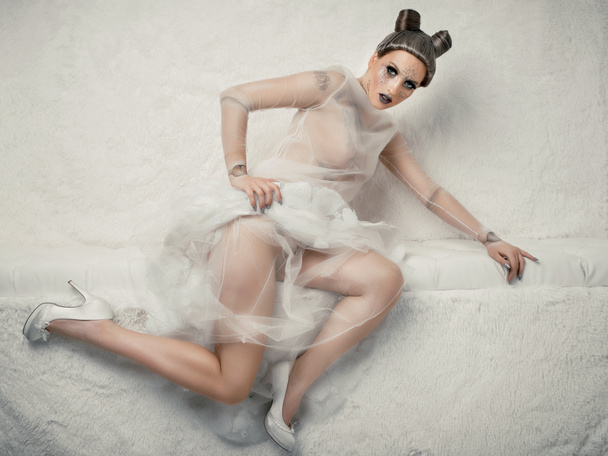 Modell mit kreativem Make-up posiert in transparentem Kleid auf weißem Hintergrund - Foto, Bild