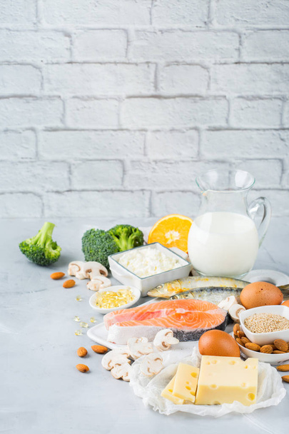 Balanced diet nutrition, healthy eating concept. Assortment of food sources rich in vitamin d and calcium, salmon, dairy products, sardines, broccoli on a kitchen table. Copy space background - Photo, Image