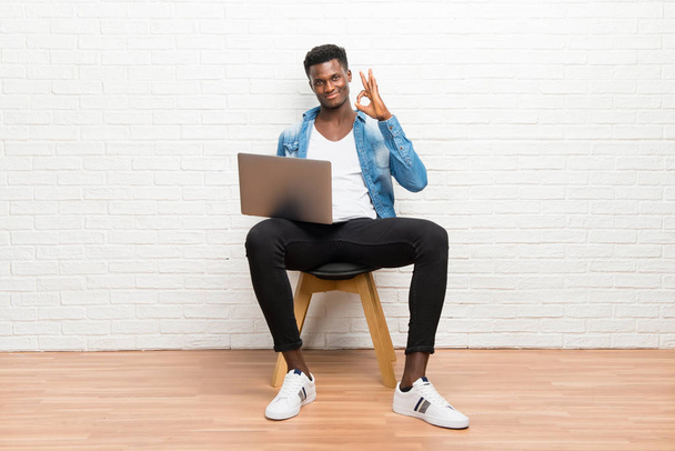 Afro american człowiek pracy z jego laptop pokazuje znak ok palcami - Zdjęcie, obraz