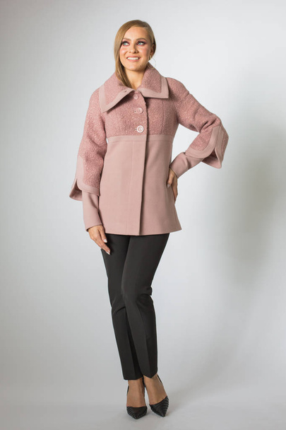 Beautiful woman posing in pink coat and black pants - Zdjęcie, obraz