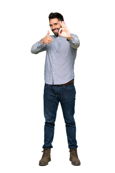 Prise de vue complète de l'homme élégant avec chemise montrant ok signe avec et donnant un geste pouce vers le haut sur fond blanc isolé
 - Photo, image