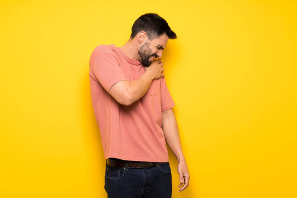 Pohledný muž přes žlutou zeď trpí bolestí v rameni pro úsilí - Fotografie, Obrázek
