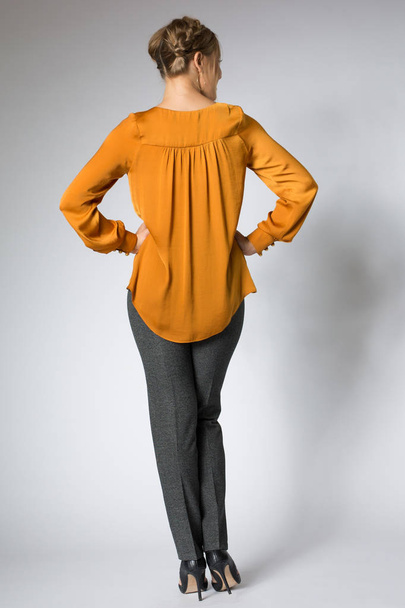 Young model posing in yellow blouse and gray pants - Foto, Imagen