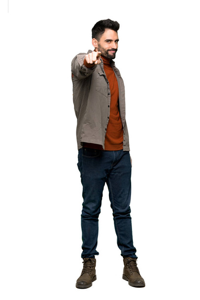 Full-length schot van knappe man met baard punten de vinger op je met een vertrouwen uitdrukking op geïsoleerde witte achtergrond - Foto, afbeelding