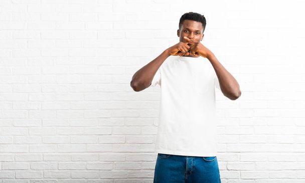 Hombre de piel oscura mostrando un signo de cerrar la boca y un gesto de silencio
 - Foto, imagen