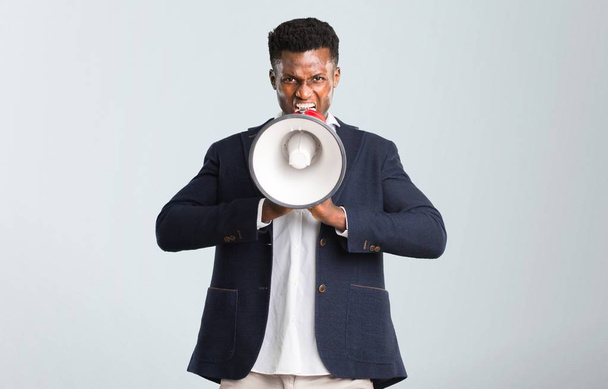 Handsome african american man wearing a jacket holding a megaphone on isolated grey background - Fotó, kép