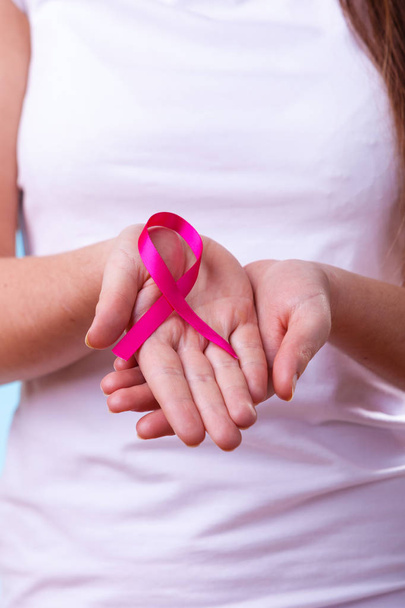 Healthcare and medicine concept - woman showing pink breast cancer awareness ribbon on hands, closeup - Foto, immagini