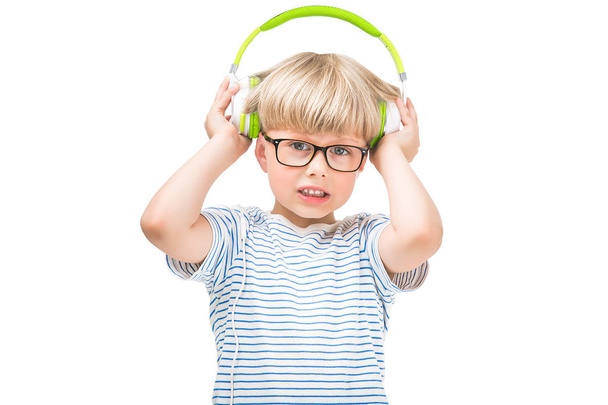 Enfant mignon à l'écoute de la musique très forte portant des écouteurs ou des écouteurs. Enfant malheureux isolé sur fond blanc écoutant la radio
. - Photo, image
