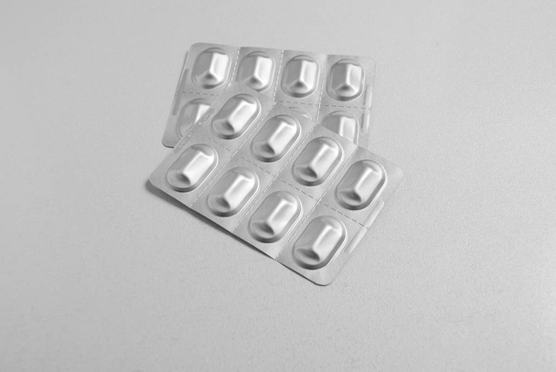 capsule pills medicine in silver aluminium blister pack isolated on white background with copy space for text. Pharmaceutical packing manufacturing concept. Blister pack with pills isolated on white. Empty blister packs isolated on white background. - Photo, image