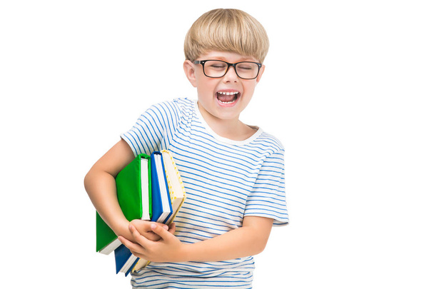 Χαριτωμένο μικρό παιδί με βιβλία και τετράδια σε απομονωμένες άσπρο φόντο. Αξιολάτρευτο παιδί ανάγνωση. Στούντιο μαθητής πυροβόλησε. Αγόρι που φορούν γυαλιά. - Φωτογραφία, εικόνα