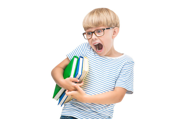Cute little child with books and notebooks on isolated white background. Adorable kid reading. Schoolboy studio shot. Boy wearing eyeglasses. - Fotó, kép