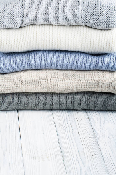 Knitted wool sweaters. Pile of knitted winter clothes on wooden background, sweaters, knitwear, space for text - Fotoğraf, Görsel