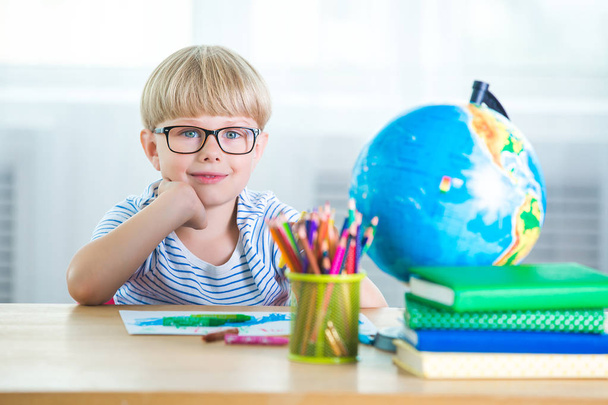 niedlichen kleinen Jungen Studie. Kind mit Büchern und Globus-Lernstunden. Schüler lernen. entzückender kaukasischer Junge macht Hausaufgaben. - Foto, Bild