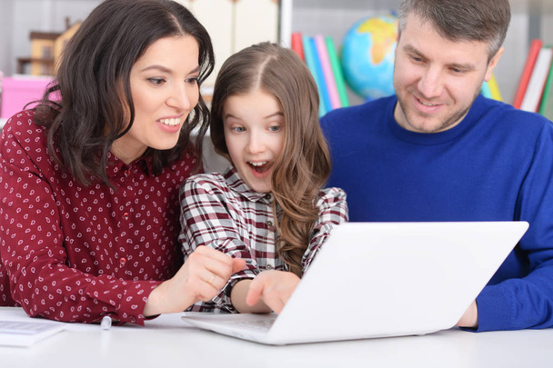 parents and daughter using laptop in room - Foto, imagen