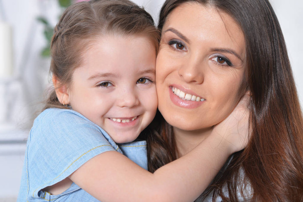 Close up portrait of little girl with mother hugging  - Photo, image