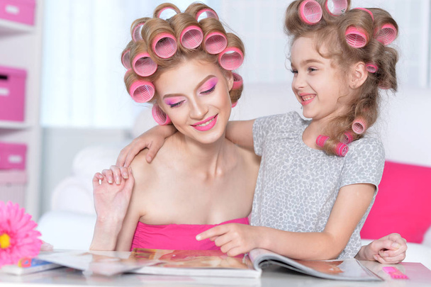 portrait of happy  Mother and little daughter with hair curlers at home - Foto, Bild