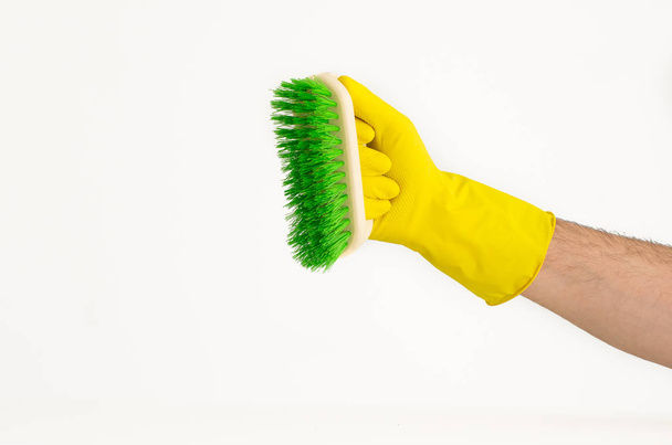 Braço masculino em luva de látex amarelo com escova de limpeza colorida
 - Foto, Imagem