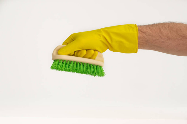 Bras masculin en gant de latex jaune avec brosse à récurer colorée
 - Photo, image