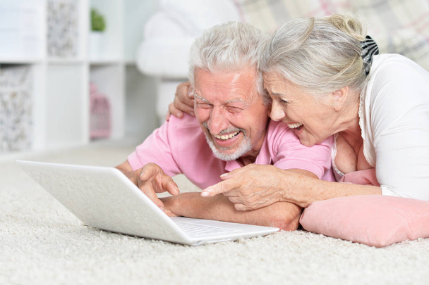 Feliz pareja de ancianos utilizando el ordenador portátil en casa
 - Foto, Imagen