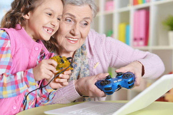 自宅のラップトップのコンピューター ゲームをプレイして彼女の孫娘とおばあちゃん - 写真・画像