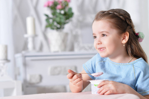 Cute little girl eating delicious yogurt - Photo, image
