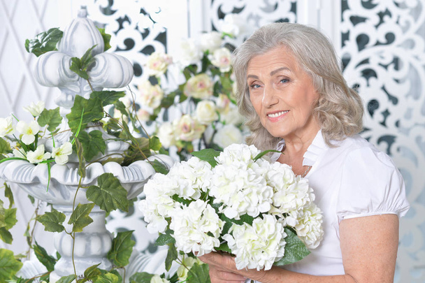 Portrait of happy senior woman posing with flowers  - Foto, Imagen