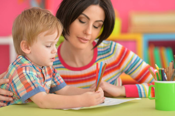молодая мать и ее маленький сын рисуют вместе с карандашами
 - Фото, изображение