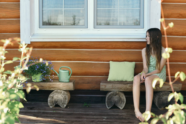 teenage girl sitting on bench beside flowers - Photo, image