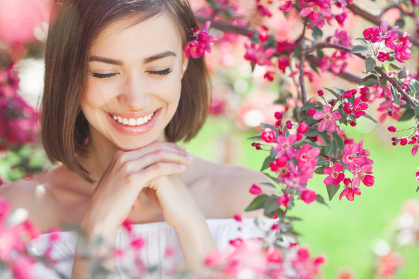Beauty portrait of young woman closeup. Attractive female in flowers. Beautiful lady outdoor. - Fotó, kép