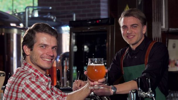 Homme heureux parlant à un barman tout en buvant de la bière au pub local
 - Photo, image