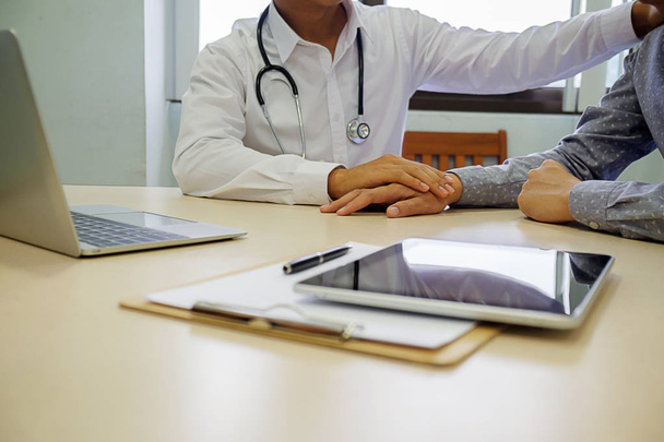 Patient listening intently to a male doctor explaining patient symptoms or asking a question as they discuss paperwork together in a consultation - Photo, Image